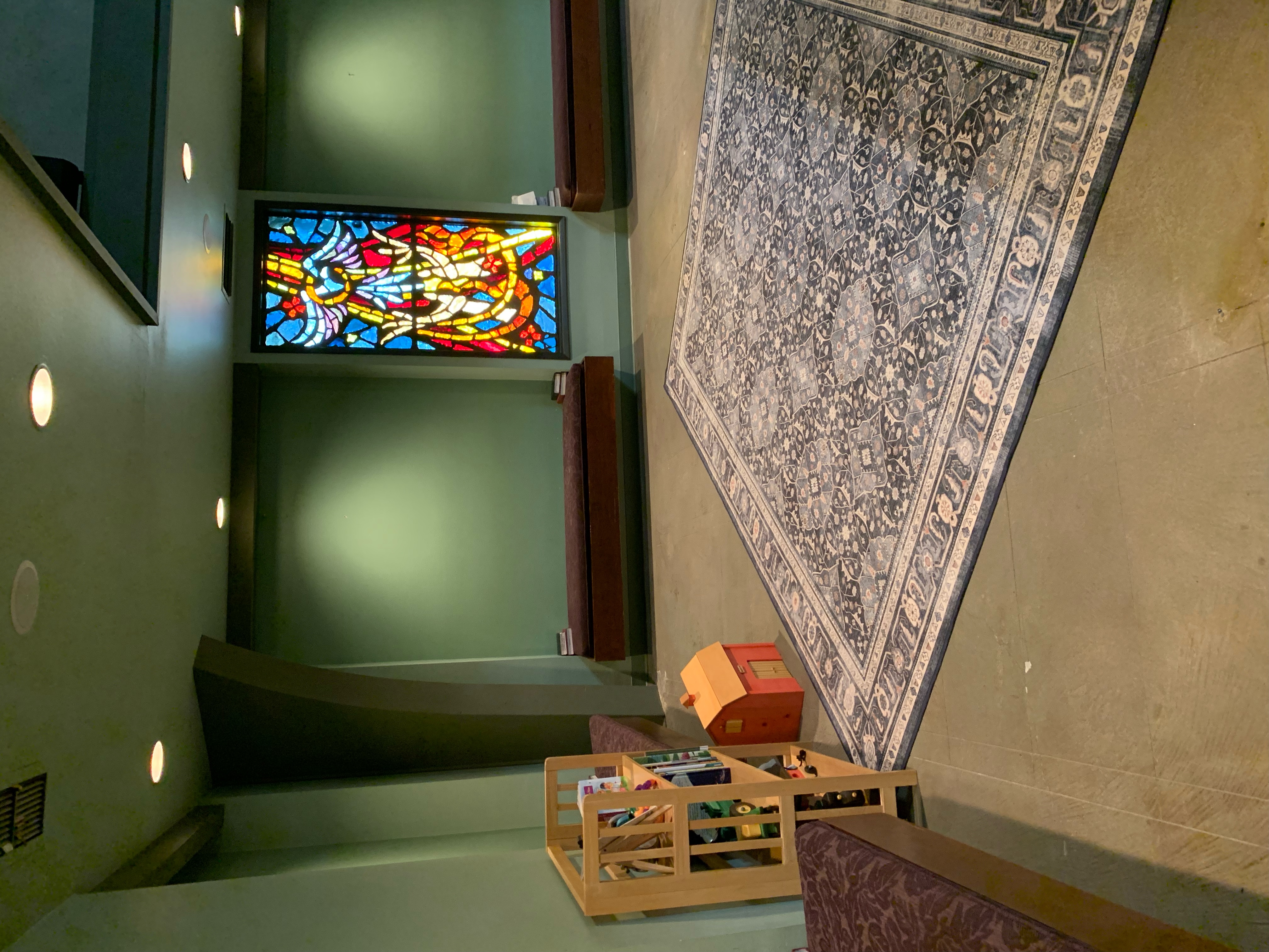 The children’s space inside St. Andrew’s, with books, toys, a rug, and stained glass