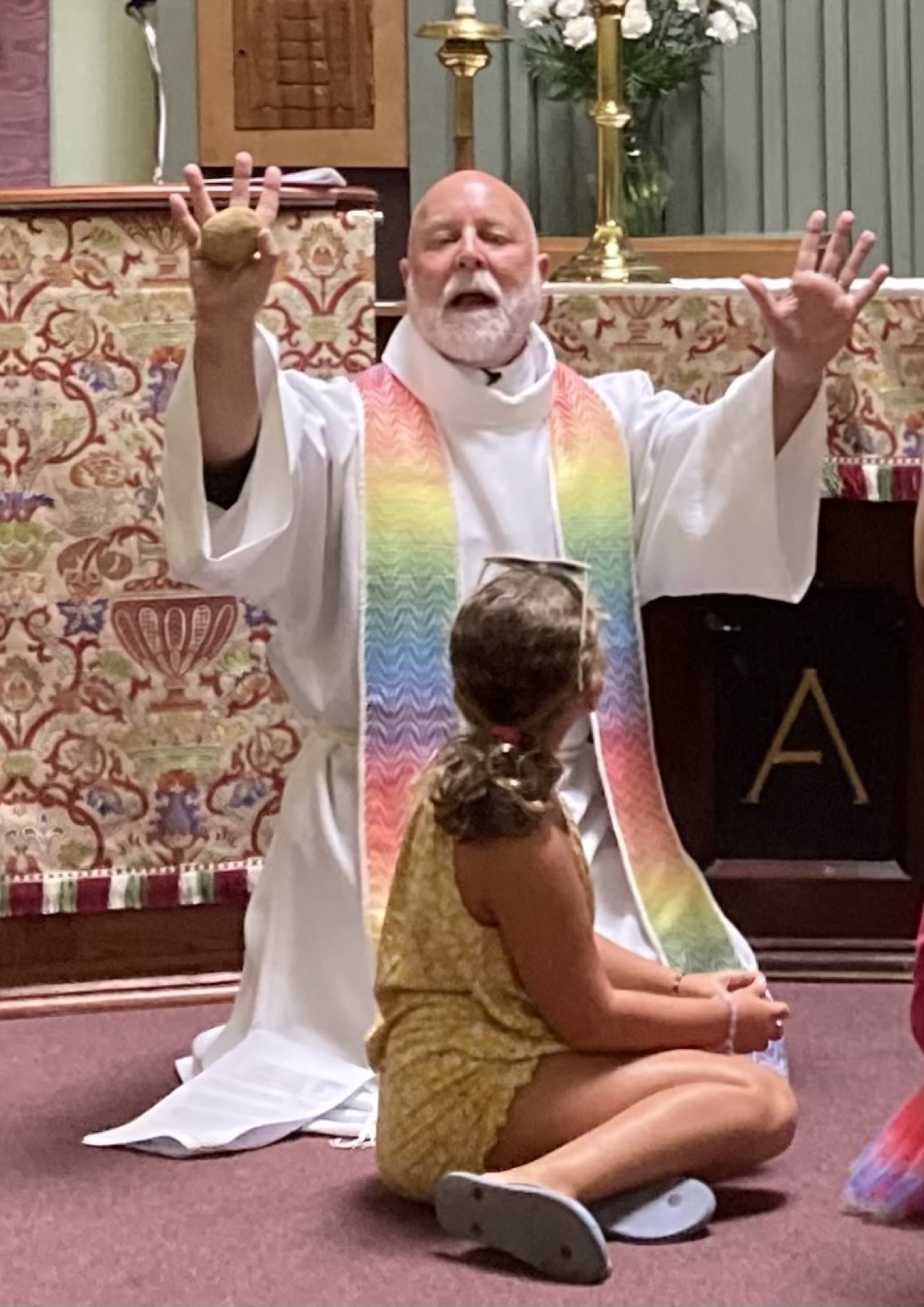 A child participating in worship with Father Bill at St. Andrew’s